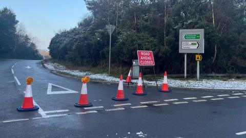 The road closure on the A3 in Surrey, between the A283 near Milford and the A333 Hindhead Tunnel. Five red cones are spread across the road to advertise the closure alongside a red sign. 