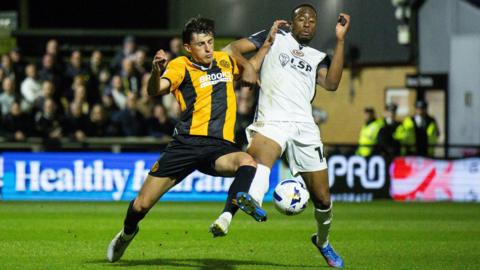Kelland Watts of Cambridge United and Nicke Kabamba of Bromley tussle for the ball