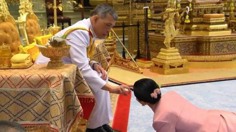 The king is seen pouring sacred water on the head of Queen Suthida