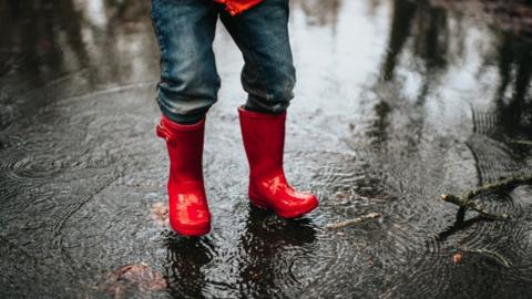 Boy splashing in puddles generic