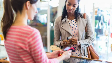 Woman paying with card at shop till