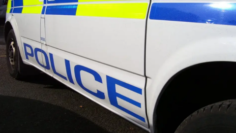 The lower half of a police car. It had POLICE written in blue capital letters on the side and alternating blue and yellow squares across the middle of the car.