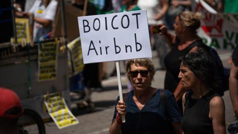 A protestor holds a banner that reads ''Boicot Airbnb'' during an anti-tourism demonstration in Barcelona, Catalunya, Spain, on June 15, 2025