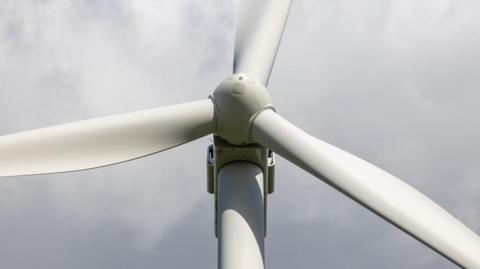 A close up of a wind turbine hub and its three blades.