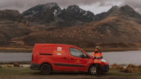 A Royal Mail van in front of a lake and mountains in Scotland.
