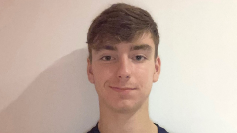 A smiling young man wearing a Wycombe Wanderers football kit.