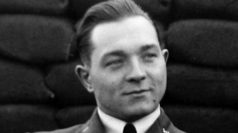 A black and white image of Sylwester Godlewski. He has short slicked back hair and is wearing an airman's suit.