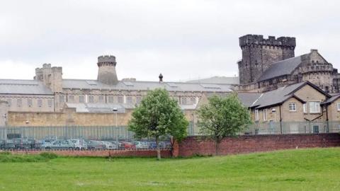 HMP Leeds, a large Victorian building which has railings around it and three turrets coming from the roof.