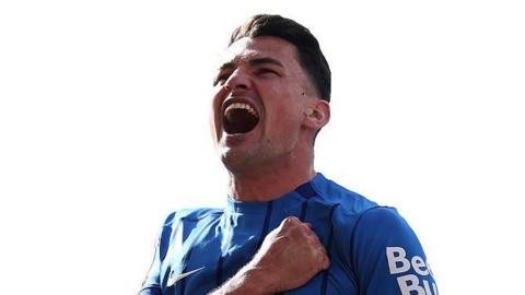 A smiling Regan Poole celebrating a goal in a blue Portsmouth shirt which his right fist clenched across his chest