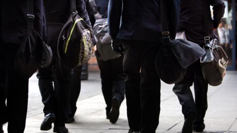 A generic stock picture of pupils - pictured from the torso down carrying school bags.