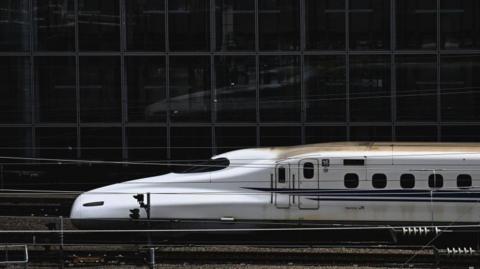 Bullet train facing left as it pulls into Tokyo station. 