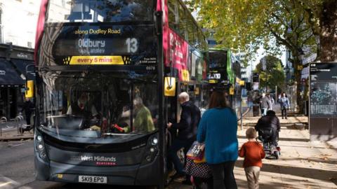 People board a bus in Birmingham city centre 