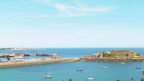 The harbour in Guernsey with a number of boats dotted on the sea.