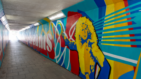 A photo of a colourful mural painted on a subway, which includes an illustration of Led Zeppelin's Robert Plant.