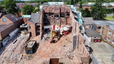Drone view of demolition work taking place on a large brick building