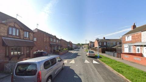 Google street view of Ryde Avenue in Hull with detached houses either side of the road, a few cars and a speed bump.