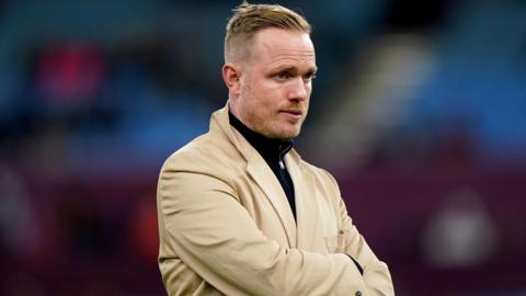 The picture shows Arsenal women's head coach Jonas Eidevall who has resigned. He is wearing a beige jacket and has his arms folded.  