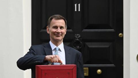 Chancellor Jeremy Hunt holds up his budget red box in front of the door of Number 11