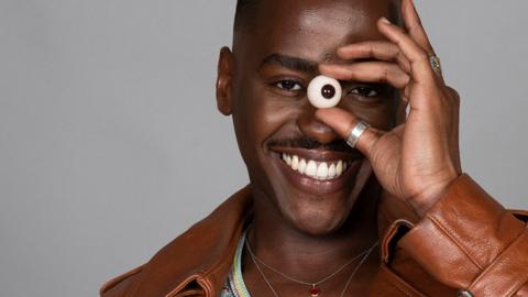Doctor Who lead actor Ncuti Gatwa holds a fake eyeball up to his face