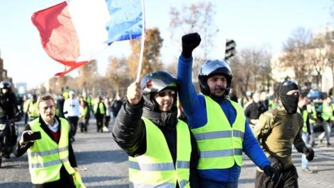 Protesters wave a French flag as they march in Paris