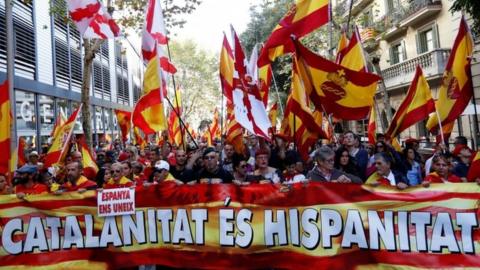 Demonstrators march with a 'Catalanitat es hispanitat' sign