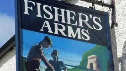 Blue sign of the Fisher's Arms with a painting of two fishermen in flat caps.