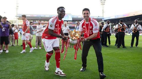 Bukayo Saka and Mikel Arteta celebrate with Premier League trophy