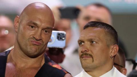 Tyson Fury looks forward as he is side eyed by Oleksandr Usyk