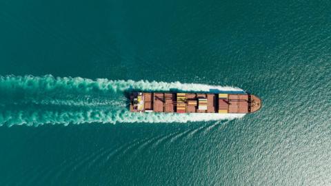 An aerial view of a container ship on a blue-green sea.