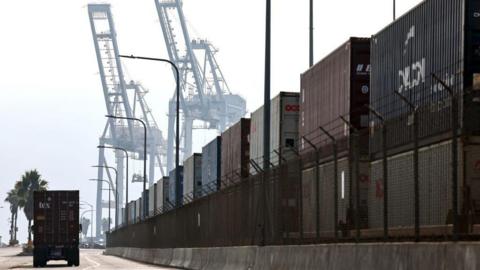 A truck drives past shipping containers stacked on rail cars at the Port of Long Beach on December 4, 2024 in Long Beach, California. 