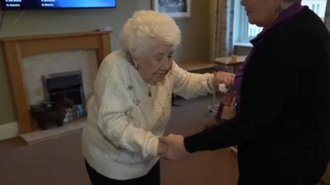 105-year-old Elsie dances, holding hands with a staff member at her care home