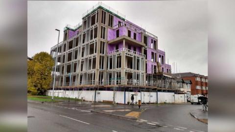 A general view picture of a six-storey flats building, which is half finished but has no windows and other materials based outside it 