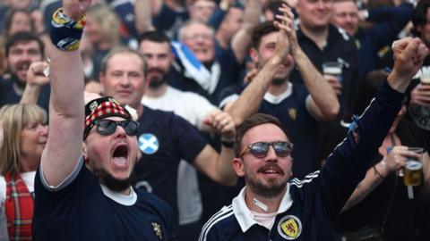 A crowd of Scotland fans, clapping and cheering. 