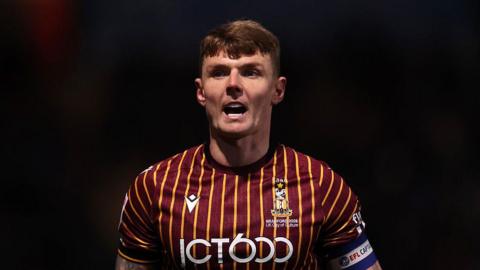 Bradford City captain Max Power shouting looking forward in night game, wearing club's home colours