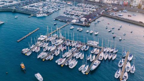 Picture shows Guernsey's Victoria Marina, with various white yachts moored up on pontoons.