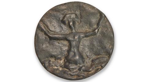 A faded bronze button depicts a woman emerging from an ocean with her arms outstretched.