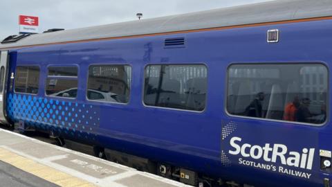 A ScotRail coach at Inverness Station. The coach's livery is blue and white.