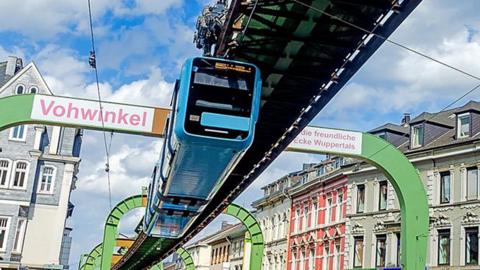 An outside monorail with a blue carriage hanging underneath a track several meters in the air.