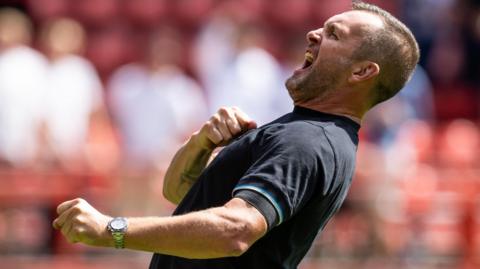 Nathan Jones holds his fist by his chest as leans back and shouts