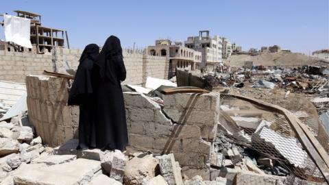 Two Yemeni women inspect the site of an alleged Saudi-led airstrike hit a neighborhood two days earlier, damaging nearby schools, in Sanaa