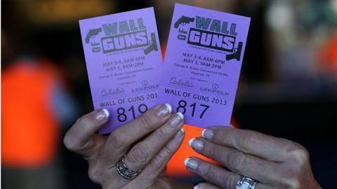 A woman tries to sell raffle tickets to win a gun from the 'Wall of Guns' during the 2013 NRA Annual Meeting and Exhibits at the George R. Brown Convention Centre on 4 May 2013 in Houston, Texas.