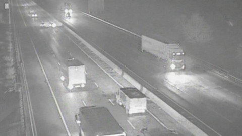 A traffic camera image of the M1 motorway at night time. Vehicles pass on each side of the road with their headlights on.