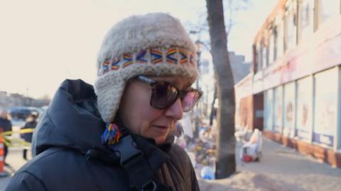 A woman talks to the BBC wearing sunglasses.