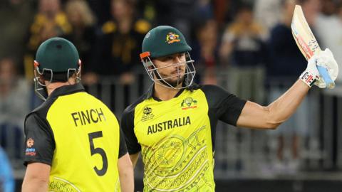 Australia's Marcus Stoinis raises his bat after passing 50