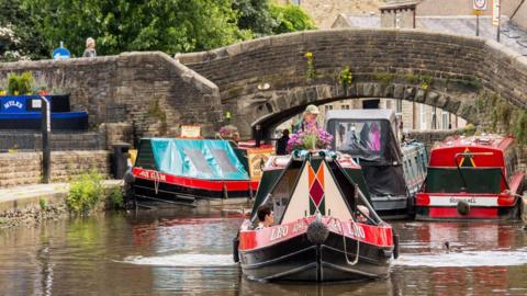 A canal with barges under a bridge in Skipton.