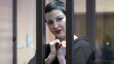 Opposition leader Maria Kolesnikova makes heart sign with her hands while in courtroom defendants cage
