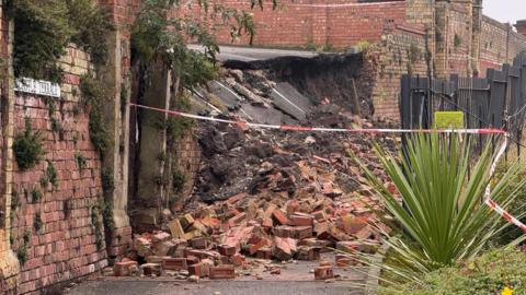 Fire service incident tape around a pile of bricks after a wall collapsed