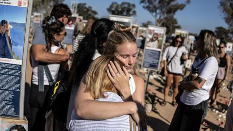 People embrace next to memorials of victims of the 2023 October 7 attacks at the Nova Festival grounds in Reim in southern Israel on the second anniversary of the attacks on October 7, 2025