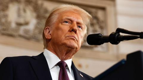 Donald Trump looks away from camera as he speaks into a microphone at the inaugural address