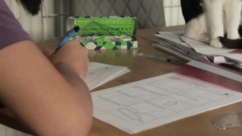 A teenage boy sat at a table in his house doing school work